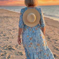Sky blue floral midi dress back view with gathered waist and ruffled tiered skirt; straw hat