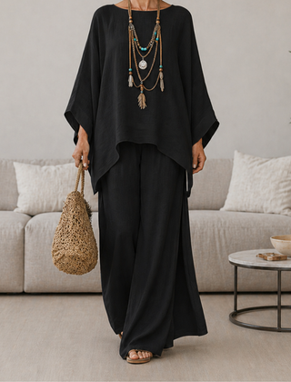 Black two-piece set with draped tunic top and wide-leg pants, long sleeves.