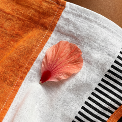 Close-up of color-block striped fabric: orange panel, white base, black stripe detail
