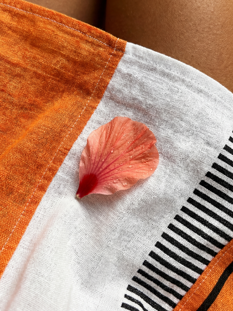 Close-up of color-block striped fabric: orange panel, white base, black stripe detail