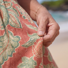 Close-up of floral beach midi dress fabric in coral with green botanical print