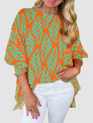 Orange loose blouse with green leaf pattern, wide sleeves, and rounded neckline