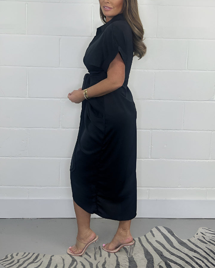 Black flared midi dress with side drape, short sleeves, and front knot detail