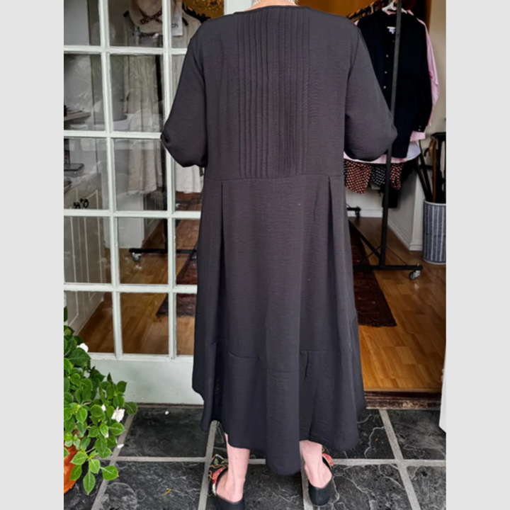Dark pleated irregular-hem midi dress, back view, with three-quarter sleeves