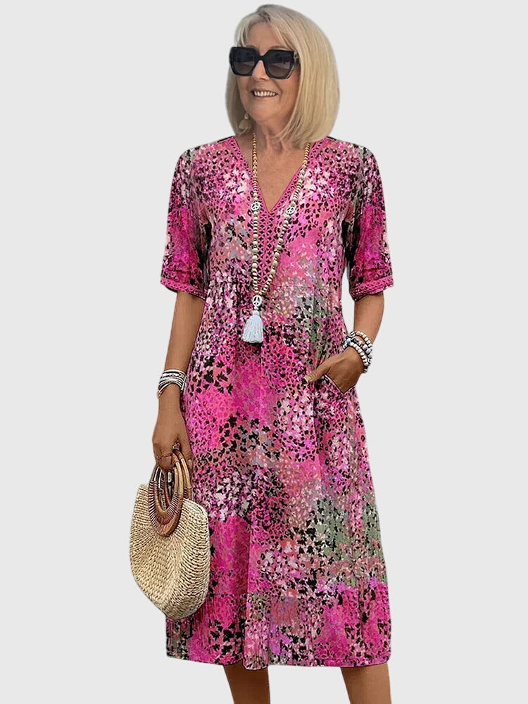Blush pink floral midi dress with V-neck, short sleeves, and white tassel detail