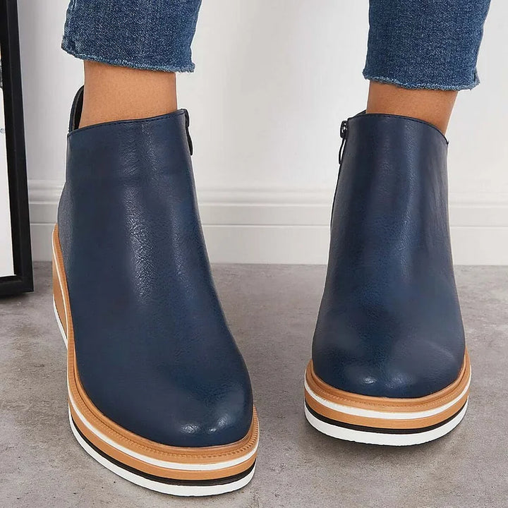 Blue Chelsea-style ankle boots with side zipper and tan platform wedge