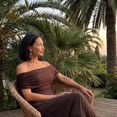 Off-shoulder draped midi dress in brown, seated side view with gathered neckline
