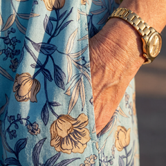 Sky blue floral midi dress fabric close-up with tan and navy flower prints on three-quarter sleeve