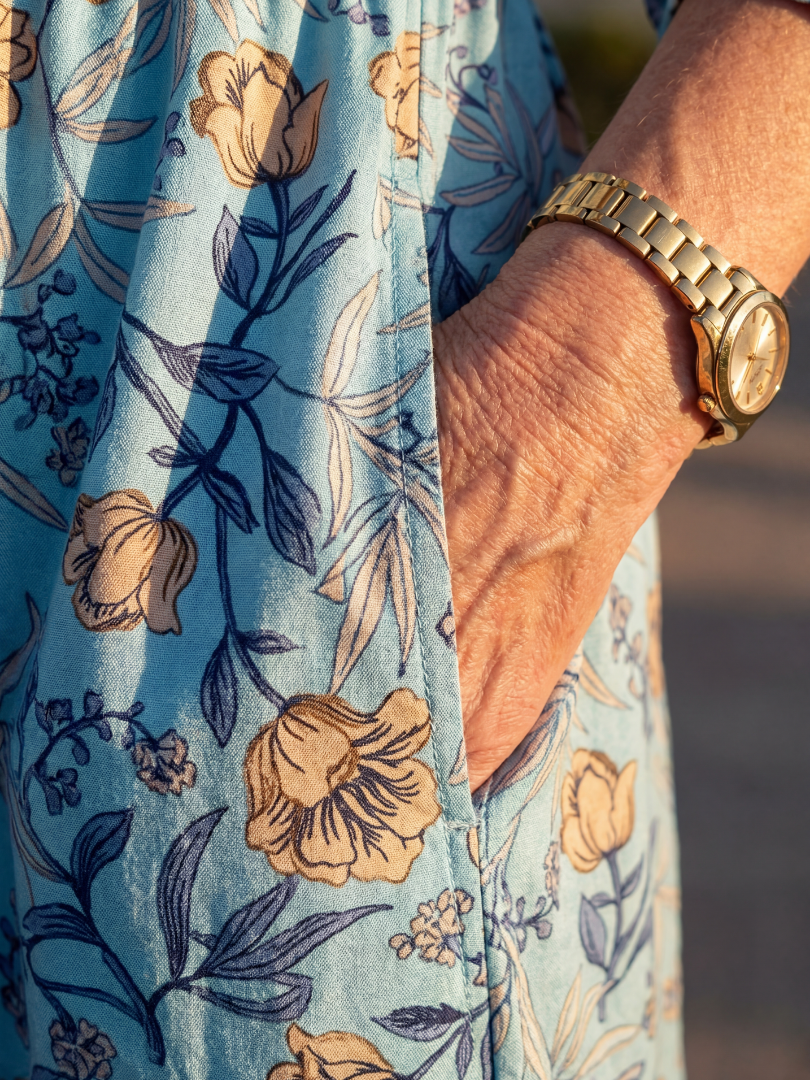 Sky blue floral midi dress fabric close-up with tan and navy flower prints on three-quarter sleeve