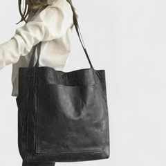 Black leather tote bag with double handles and front pocket seam