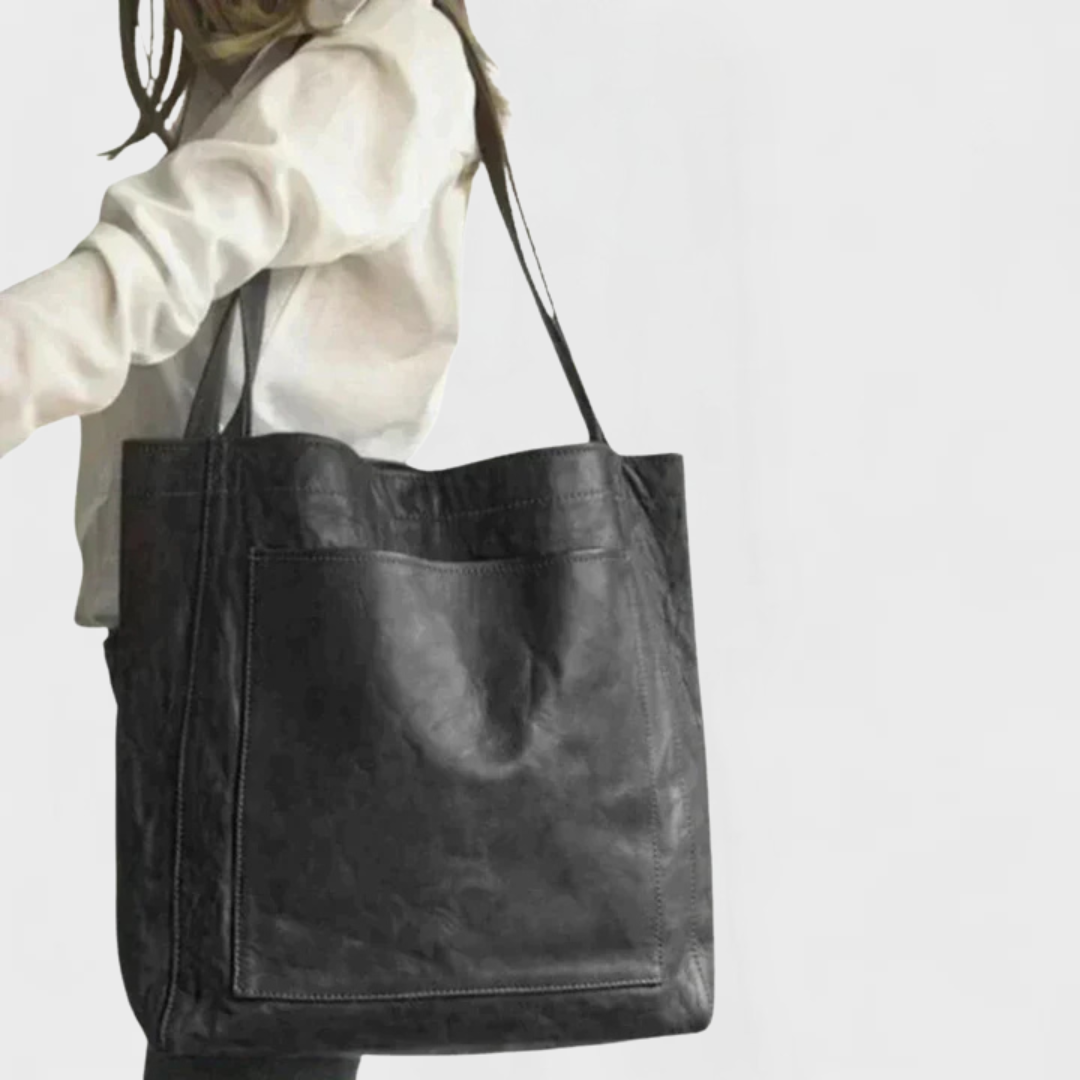 Black leather tote bag with double handles and front pocket seam