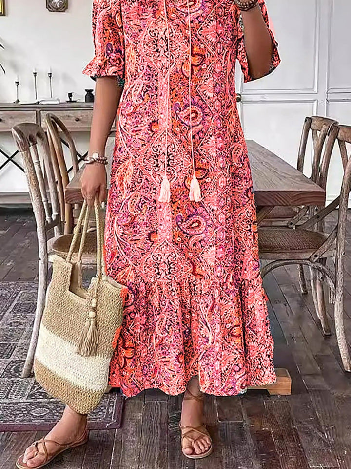 Pink-red paisley Boho Grace dress close-up, tassel-tie neckline and tiered skirt