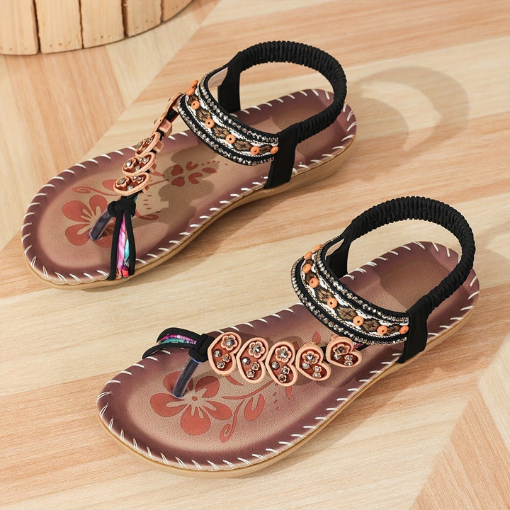 Brown open-toe sandals with black elastic straps and beaded floral panel