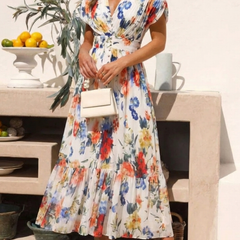 Floral pleated midi dress with short sleeves and V-neck; model holding a white bag