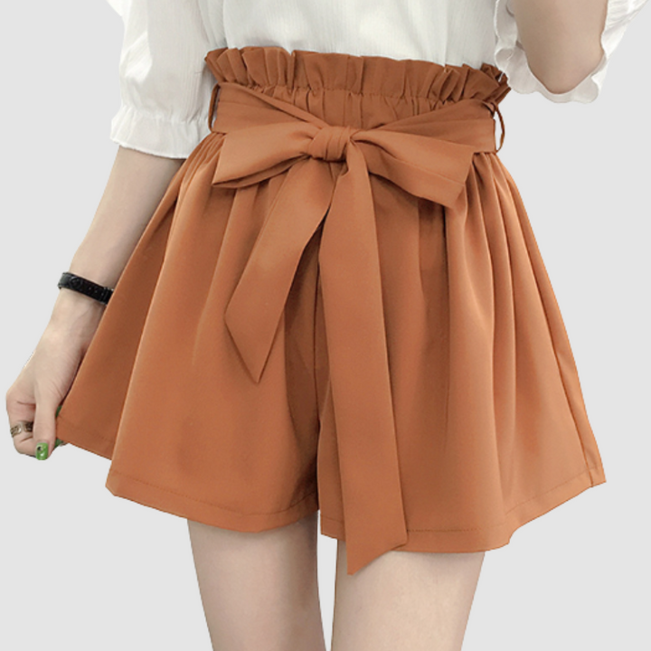 Tan paperbag waist shorts with tied bow and pleated elastic waistband.