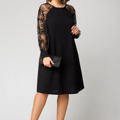 Black midi dress with sheer lace sleeves and long cuff detail; handheld clutch.