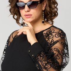 Black dress with sheer lace sleeves, round neck, and button cuff detail