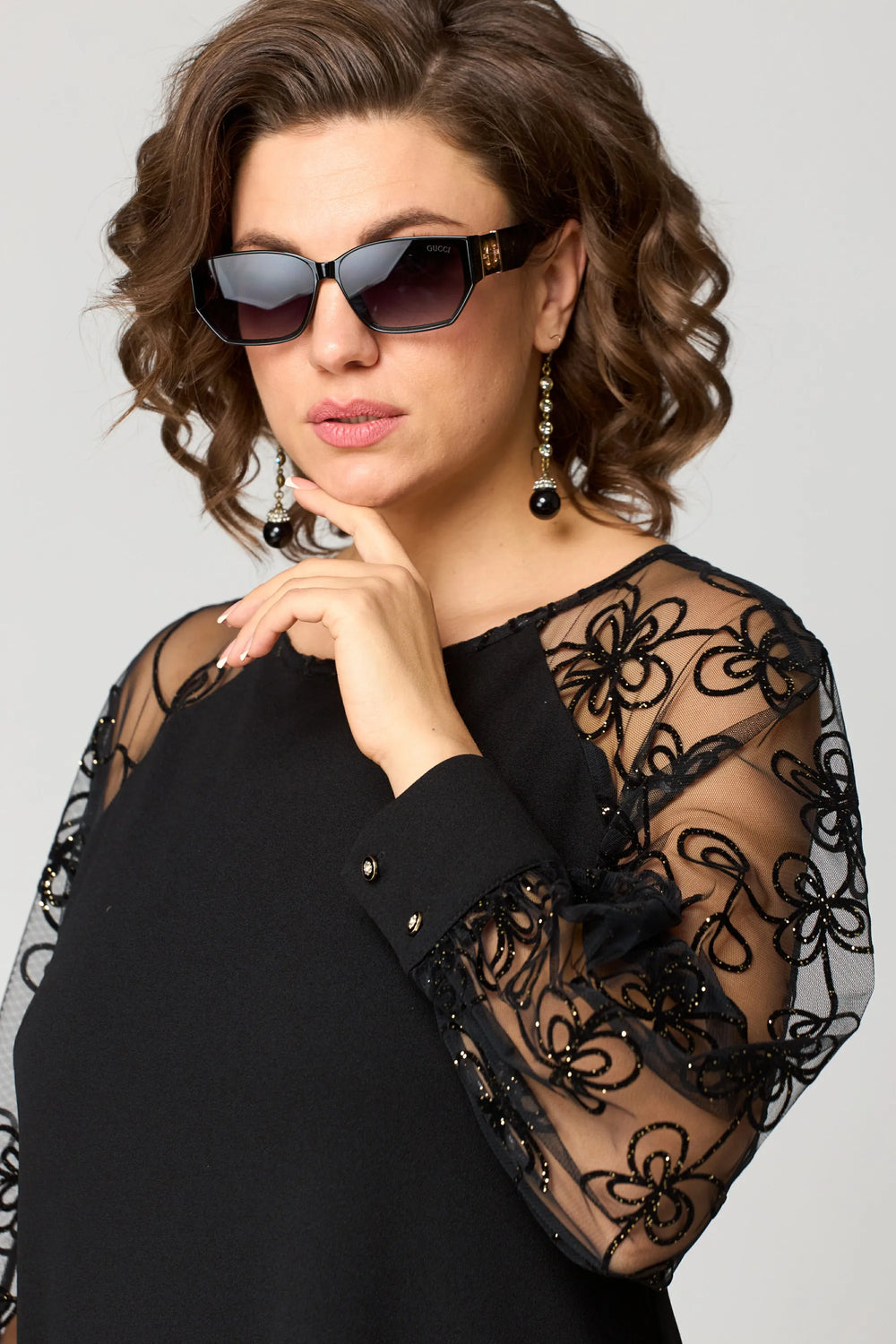 Black dress with sheer lace sleeves, round neck, and button cuff detail
