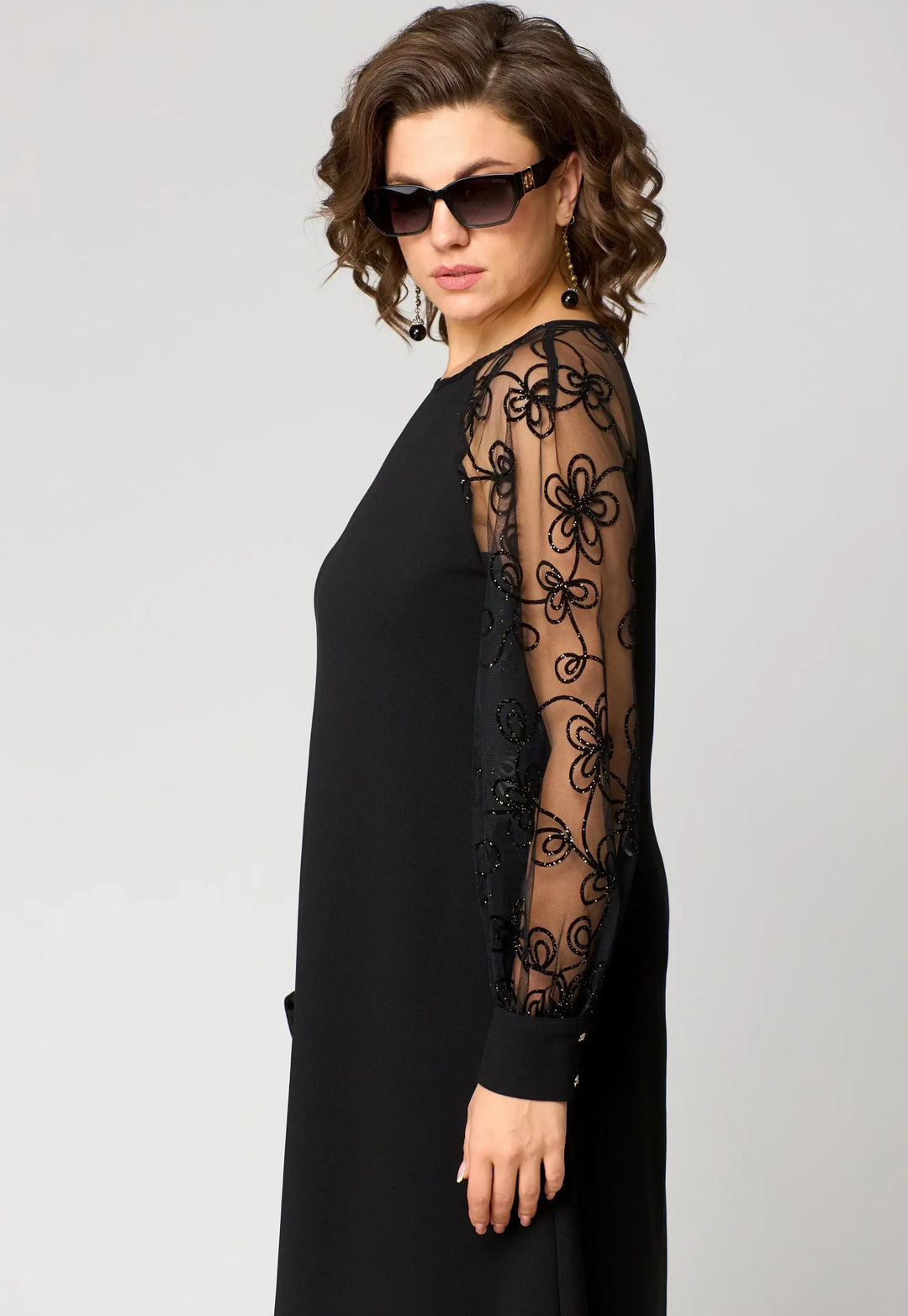 Black A-line dress with sheer lace panel sleeve and long sleeves.