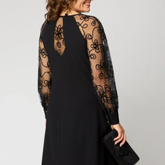 Black dress back view with sheer lace sleeves and swirling lace embroidery.