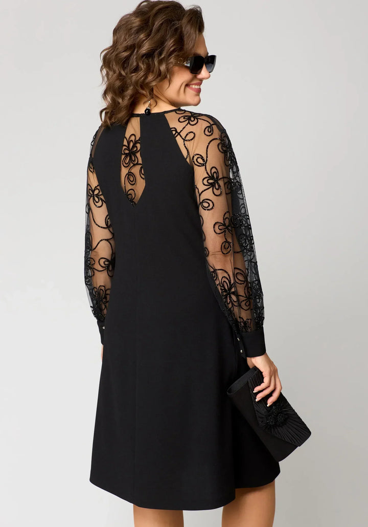 Black dress back view with sheer lace sleeves and swirling lace embroidery.