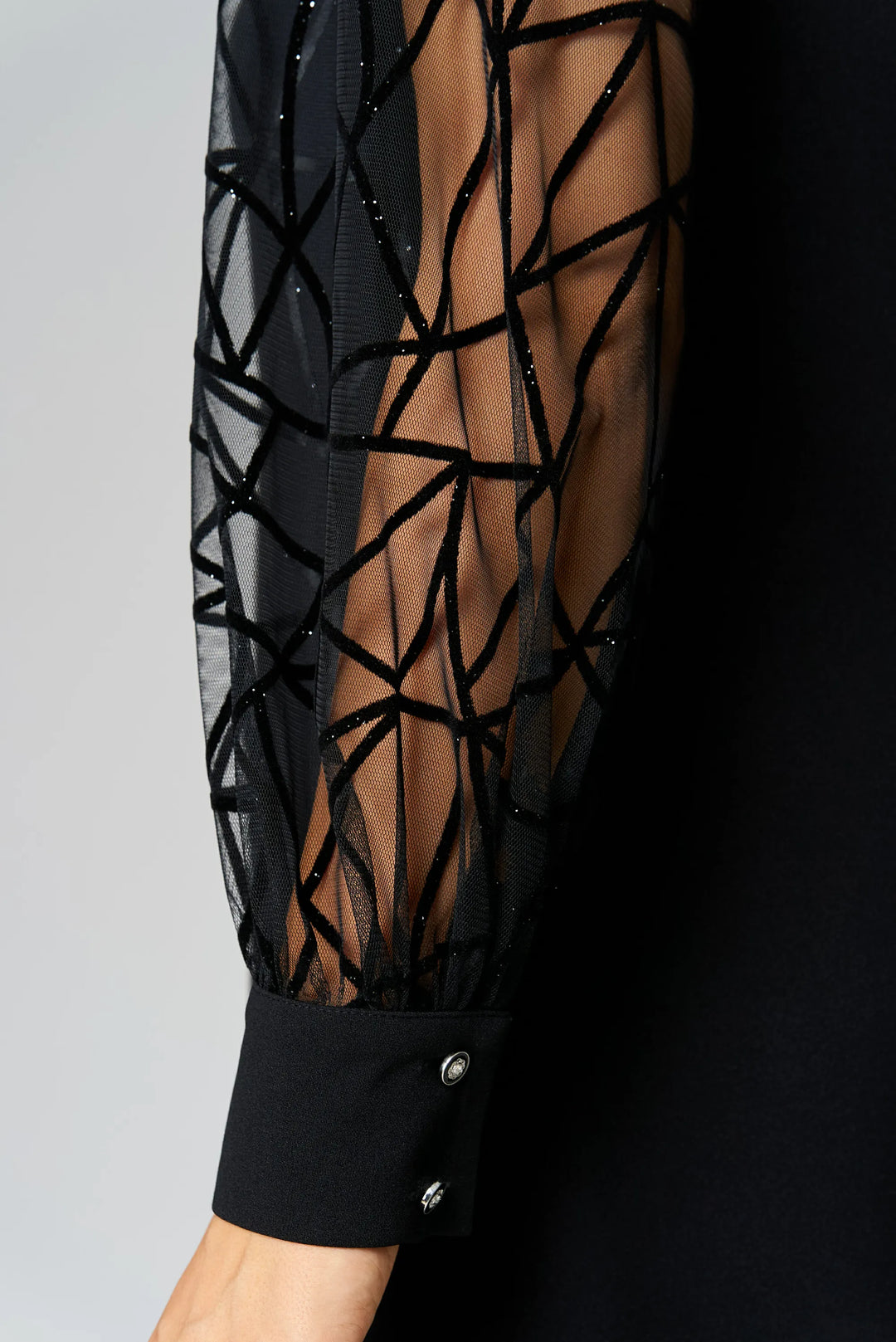 Black tunic dress sleeve close-up with sheer lattice panel and button cuff