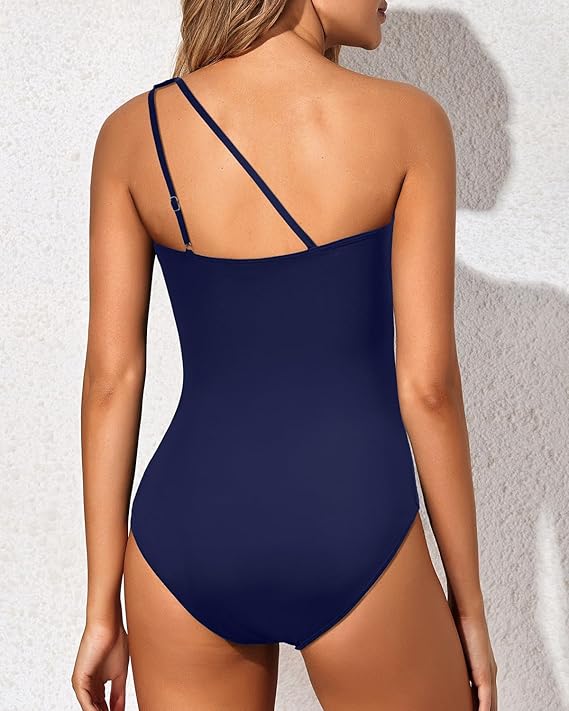 One-shoulder navy blue swimsuit with open back and thin adjustable straps.