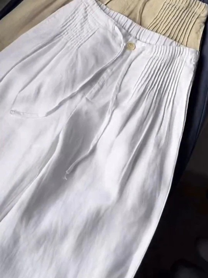 White wide-leg trousers with elastic waistband, drawstring cord, and front button