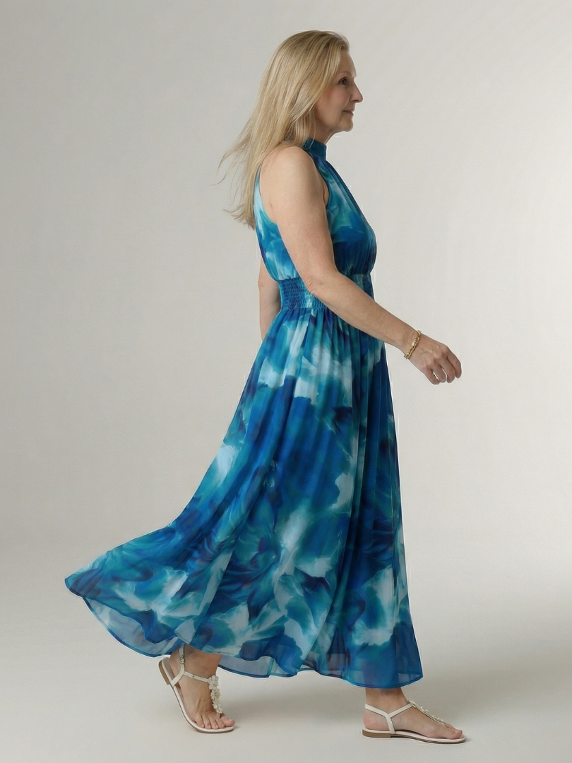 Blue tie-dye halter midi dress, side view with gathered waist and flowing skirt