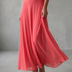 Off-shoulder draped midi dress in coral pink, close-up of flowing skirt hem