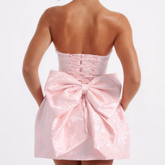 Pink jacquard mini dress back view with strapless fit and big waist bow