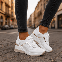 White lace-up sneakers with perforated toe, lace-up front, and thick sole.
