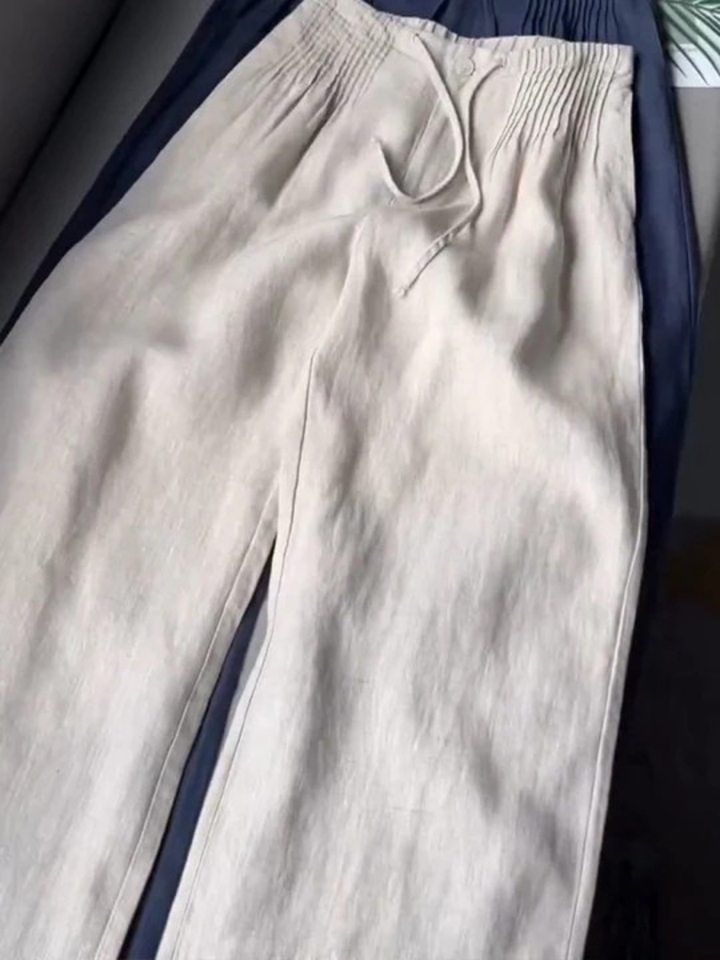 White wide-leg trousers with gathered elastic waistband, drawstring, and button