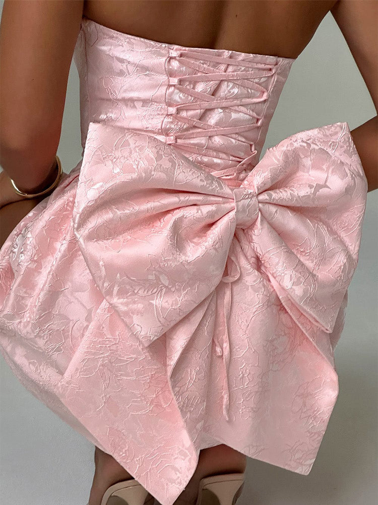 Pink jacquard mini dress close-up of corset lacing and voluminous bow-knot skirt