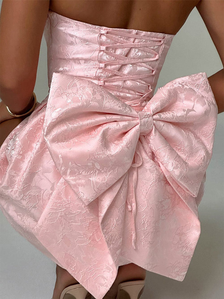 Pink jacquard mini dress close-up of corset lacing and voluminous bow-knot skirt