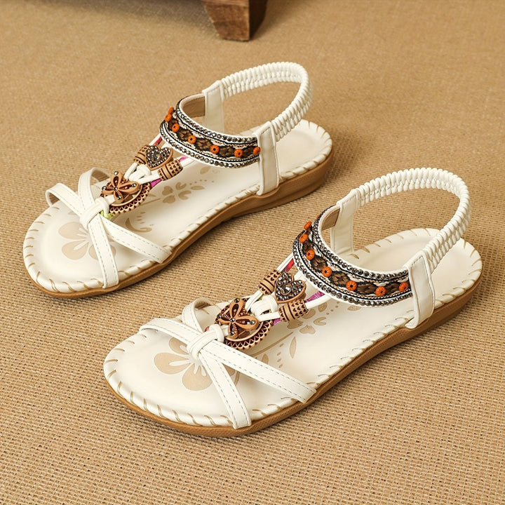 White boho flat sandals with open toe, beaded trim and bow charm, woven sole