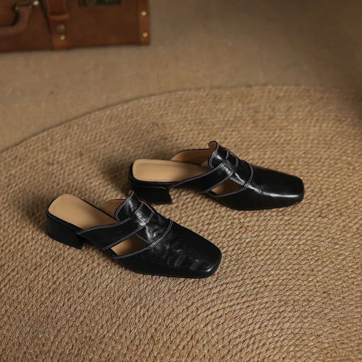 Black leather mules pair with square toe, T-strap buckle, and low block heels