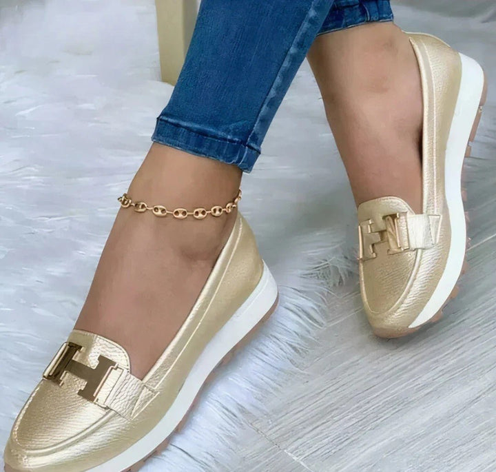 Sleek orthopedic loafers, gold slip-on with buckle detail and white sole.