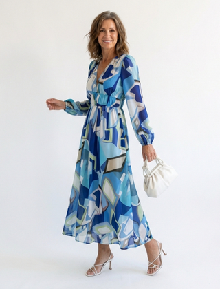 Althea long-sleeve graphic maxi dress with V-neck and gathered waist, blue tones; holding bag
