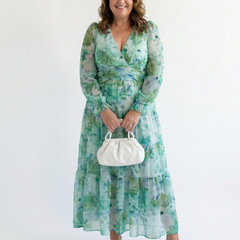 Althea long-sleeve floral maxi dress with gathered waist, tiered hem, green; holding mini bag