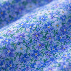 Blue floral fabric close-up with small blossoms and light green highlights