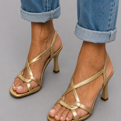 Gold strappy open-toe heeled sandals with thin cross straps and ankle look