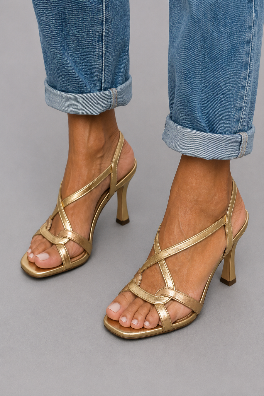 Gold strappy open-toe heeled sandals with thin cross straps and ankle look