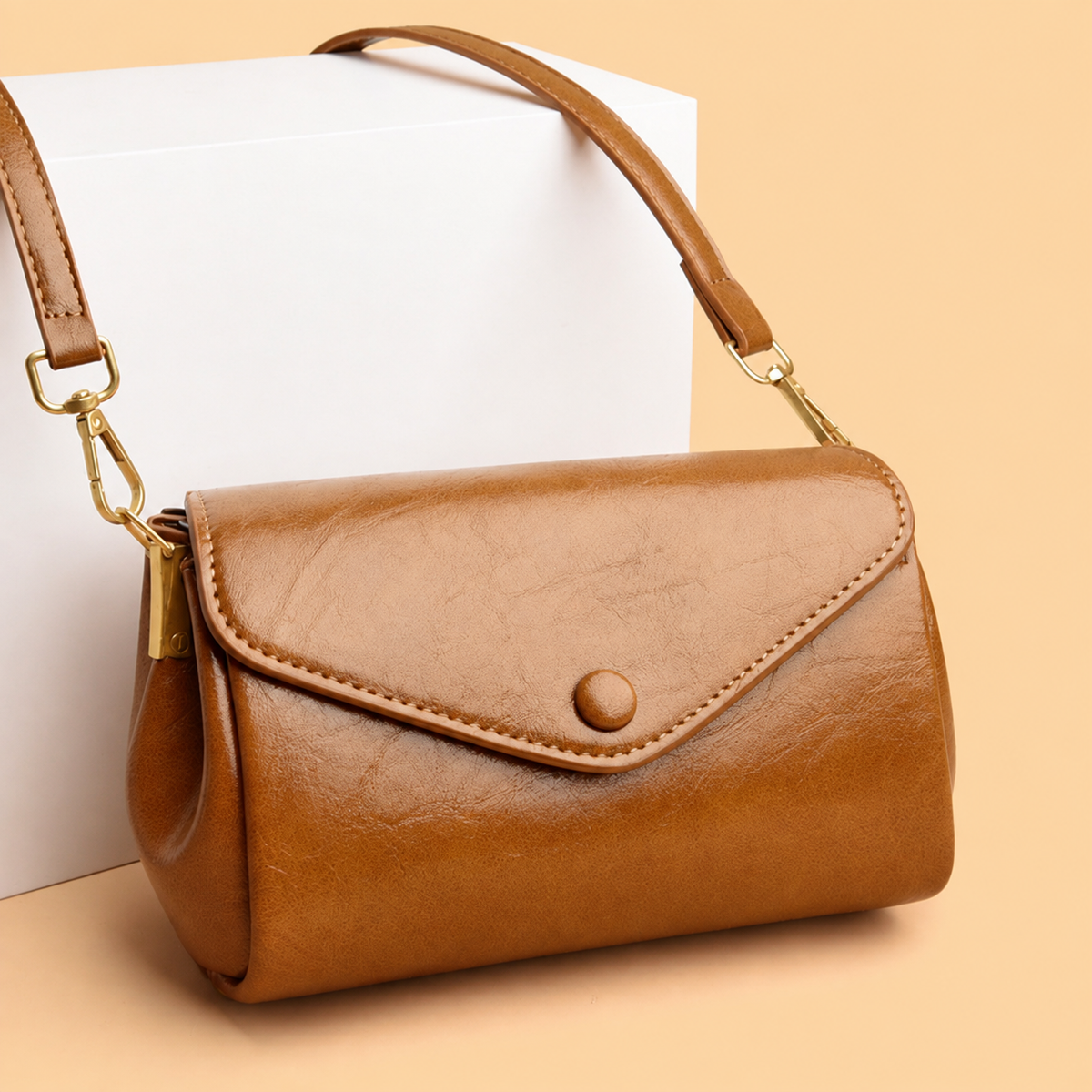 Light brown classic crossbody bag with front flap, snap button, and adjustable shoulder strap