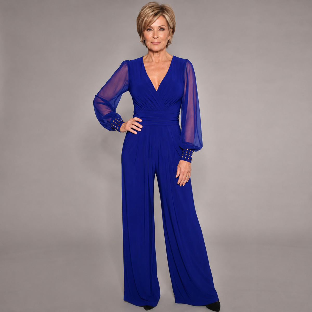 Blue evening jumpsuit with V-neck, ruched waist, sheer long sleeves, and wide legs.