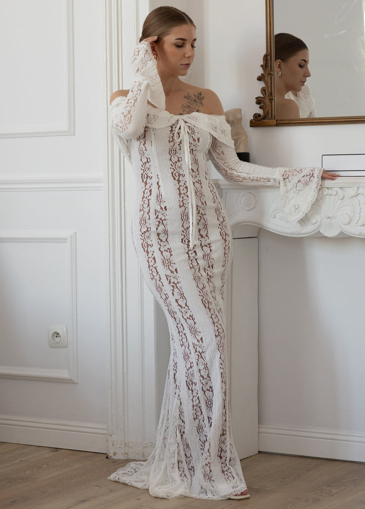 White lace maxi dress with off-shoulder neckline, long sleeves, and vertical lace detailing.