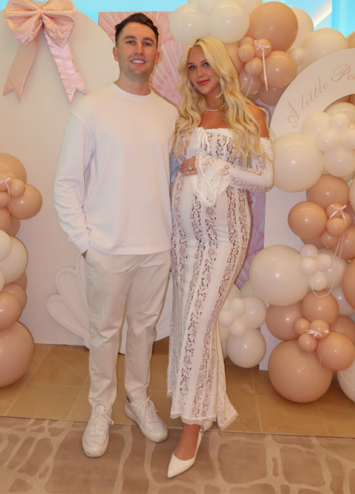 White lace maxi dress with off-shoulder neckline and long sleeves; ornate vertical lace pattern.