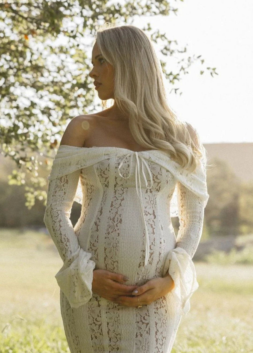 White lace maxi dress, off-shoulder neckline and long sleeves; fitted bodice, flowing skirt.