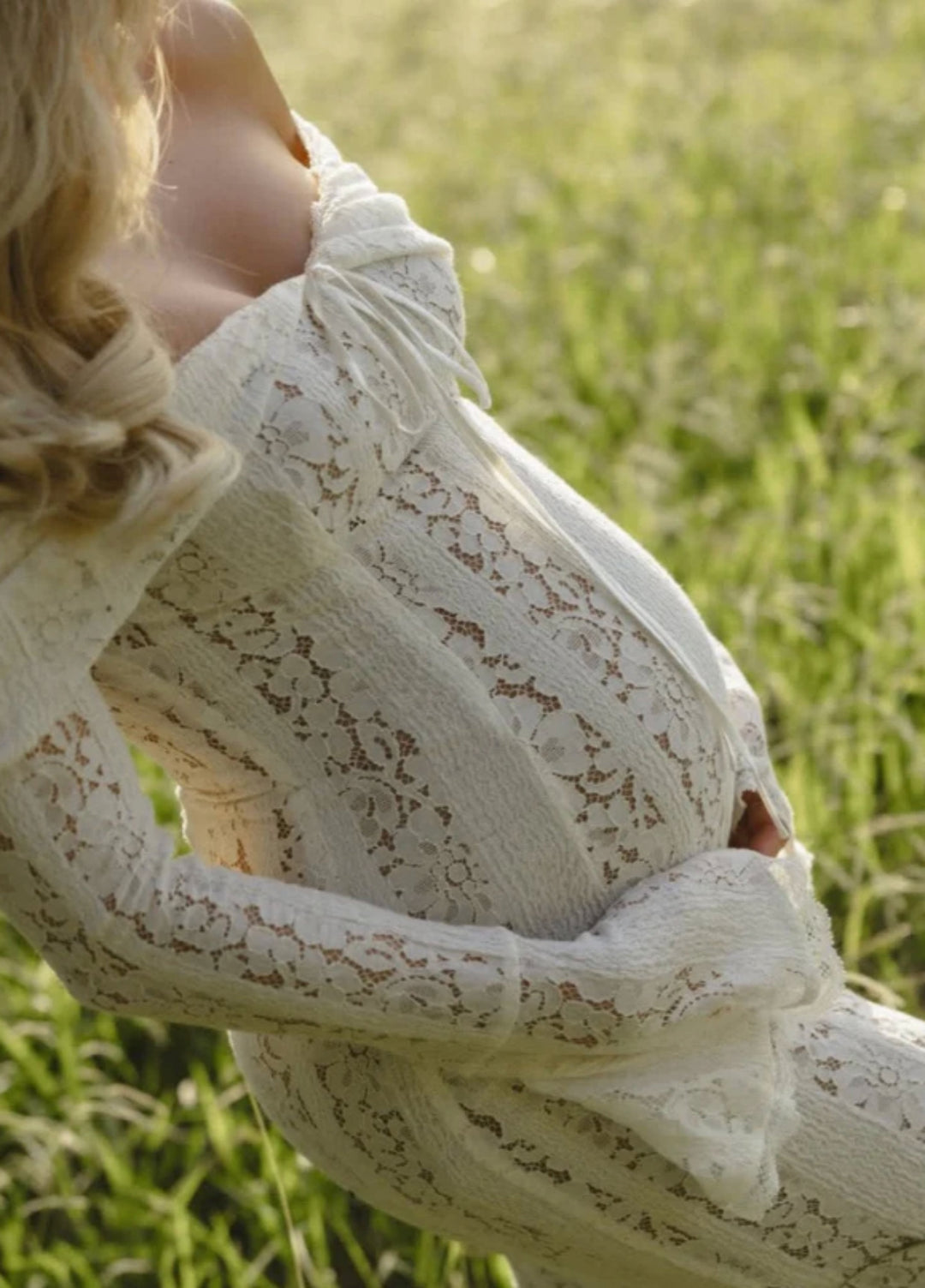 White lace maxi dress close-up: long lace sleeve and textured vertical lace overlay.