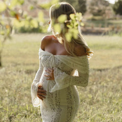 White lace maxi dress with off-shoulder neckline and long sleeves; fitted lace bodice.